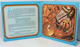An open book or booklet spread showing two illustrated pages with text on the left and a colorful photograph of traditional drums on the right, set against a plain white background.