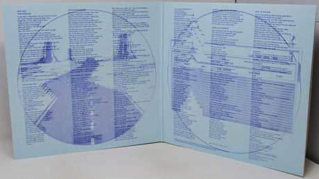 An open book or booklet spread open on a white surface, showing printed blue circular diagrams and text on pale blue pages.