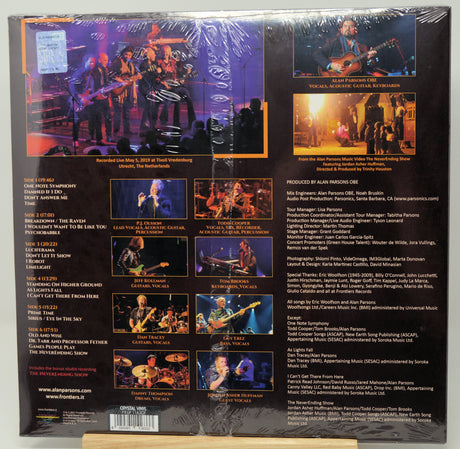 The back cover of a vinyl record sleeve for Alan Jackson's 'You'll Never Love Again', wrapped in protective plastic. The black background features multiple color photographs of the band performing live, along with track listings, credits, and barcode details.