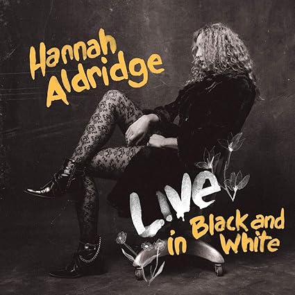 Album cover with a person sitting on a chair, text 'Hannah Aldridge Live in Black and White', and a black and white color scheme.
