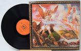 A vinyl record partially pulled from its illustrated album cover, showing a black record with an orange center label beside a square cover featuring a fantasy scene with angels and a landscape.