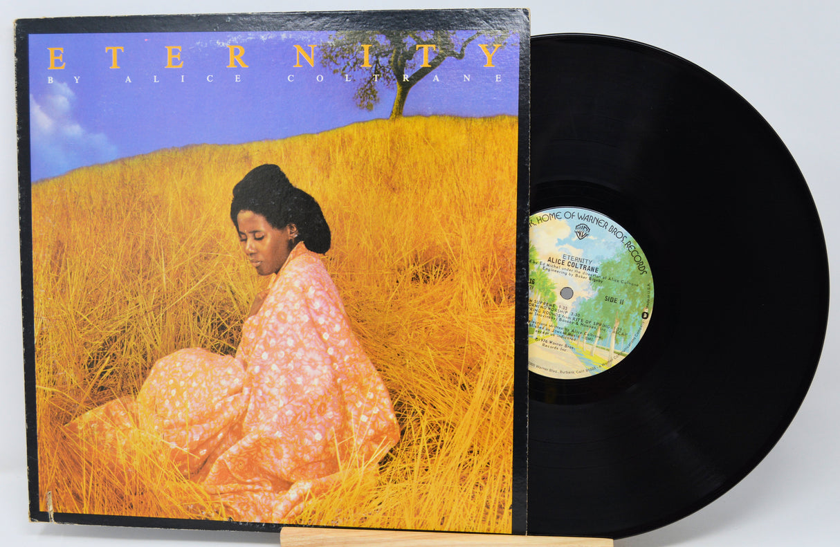 A vinyl record partially pulled from its sleeve, showing the album cover art for 'Eternity' by Aretha Franklin. The cover depicts Aretha seated in a golden field under a blue sky, with the black vinyl record visible beside it.