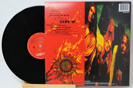 A vinyl record album shown with the black record partially pulled from its sleeve, photographed on a white background. The sleeve features a fiery red-orange front cover with a central circular logo and a photo of four band members on the right side.