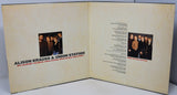 An open printed booklet or album insert with cream-colored pages, showing a small group photo, text, and song listings. The visible title reads 'ALISON KRAUSS & UNION STATION' with smaller text below.