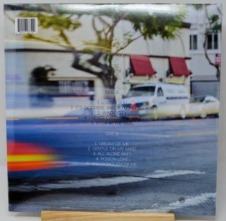 Vinyl record album cover for A$AP Rocky's 'WAP' on a wooden display stand. The back of the cover features a blurred street scene with cars and trees, track listings for Side A and Side B, and a barcode.