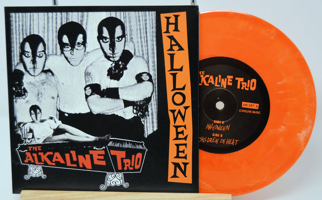 Orange vinyl record with black label featuring 'The Alkaline Trio' and black and white album cover on a white background