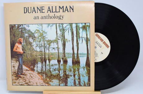 A vinyl record titled 'Duane Allman - An Anthology' with an image of a man standing in a forest on the cover.