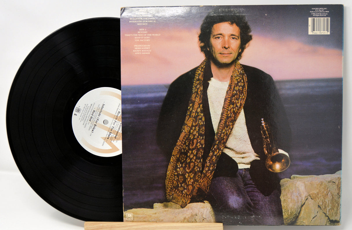 Vinyl record with cover art of a man holding a instrument by the ocean.