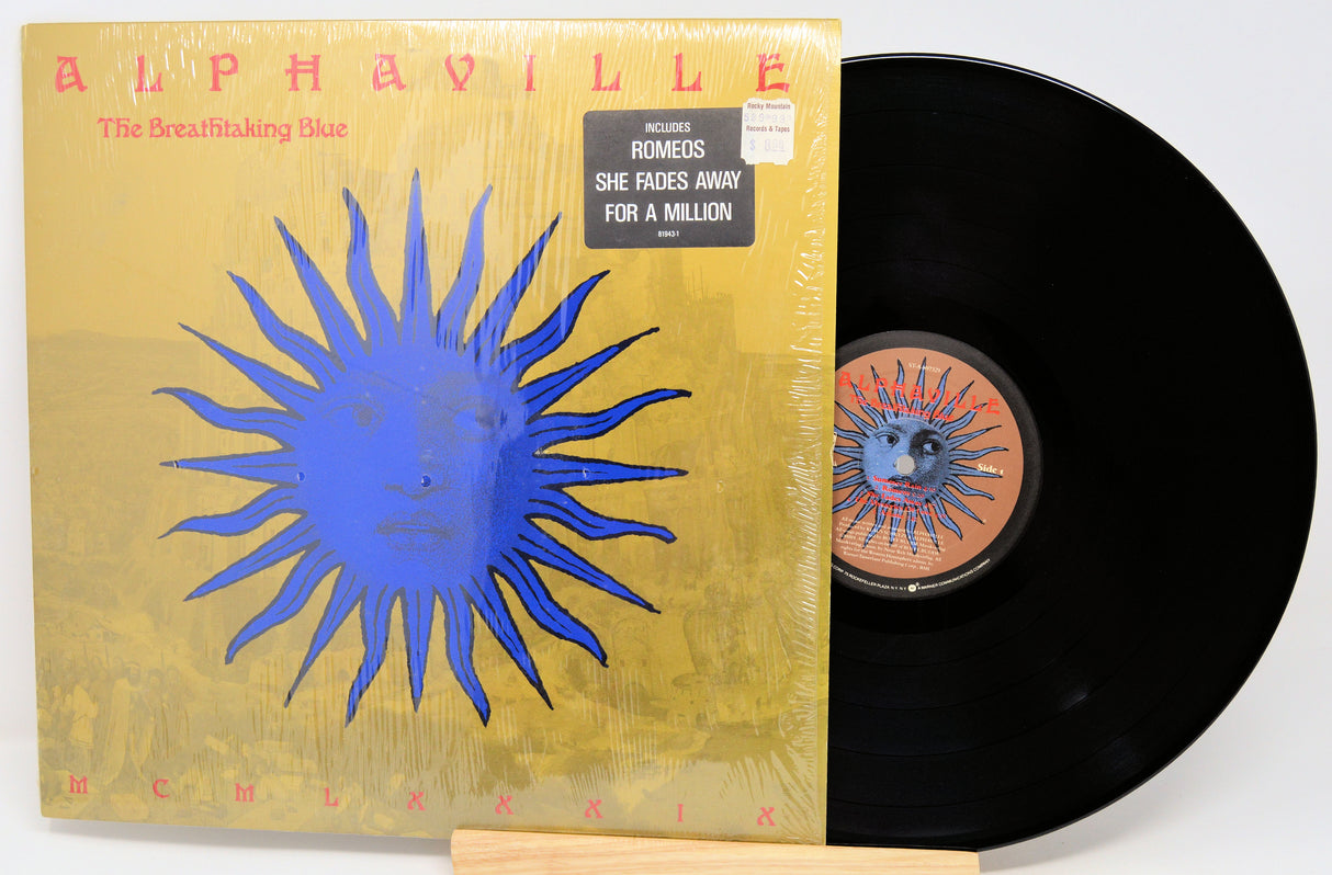 Vinyl record with 'Alphaville' album cover featuring a blue sun design on a yellow background.