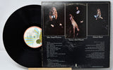 Vinyl record with cover featuring three portraits and text on a gray background