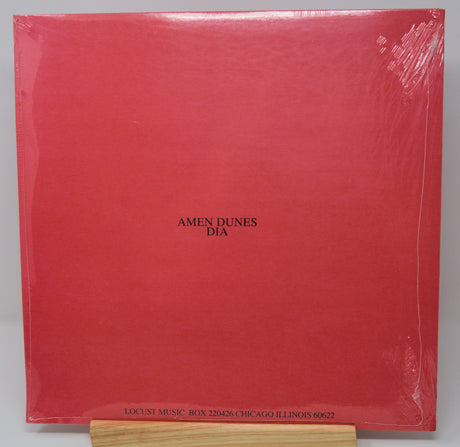 A red vinyl record cover featuring a black and white image of a person's face superimposed on a red background with the text 'DIA' at the top.