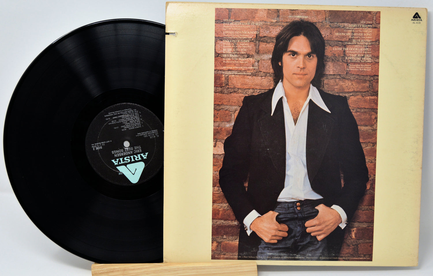 Vinyl record with Arista label for Eric Andersen 'Tight In The Night' and rear cover showing a picture of him standing against a brick wall and white text for the song titles and credits.