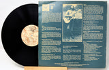 Vinyl record with its cover featuring text and a photo of a person playing guitar.