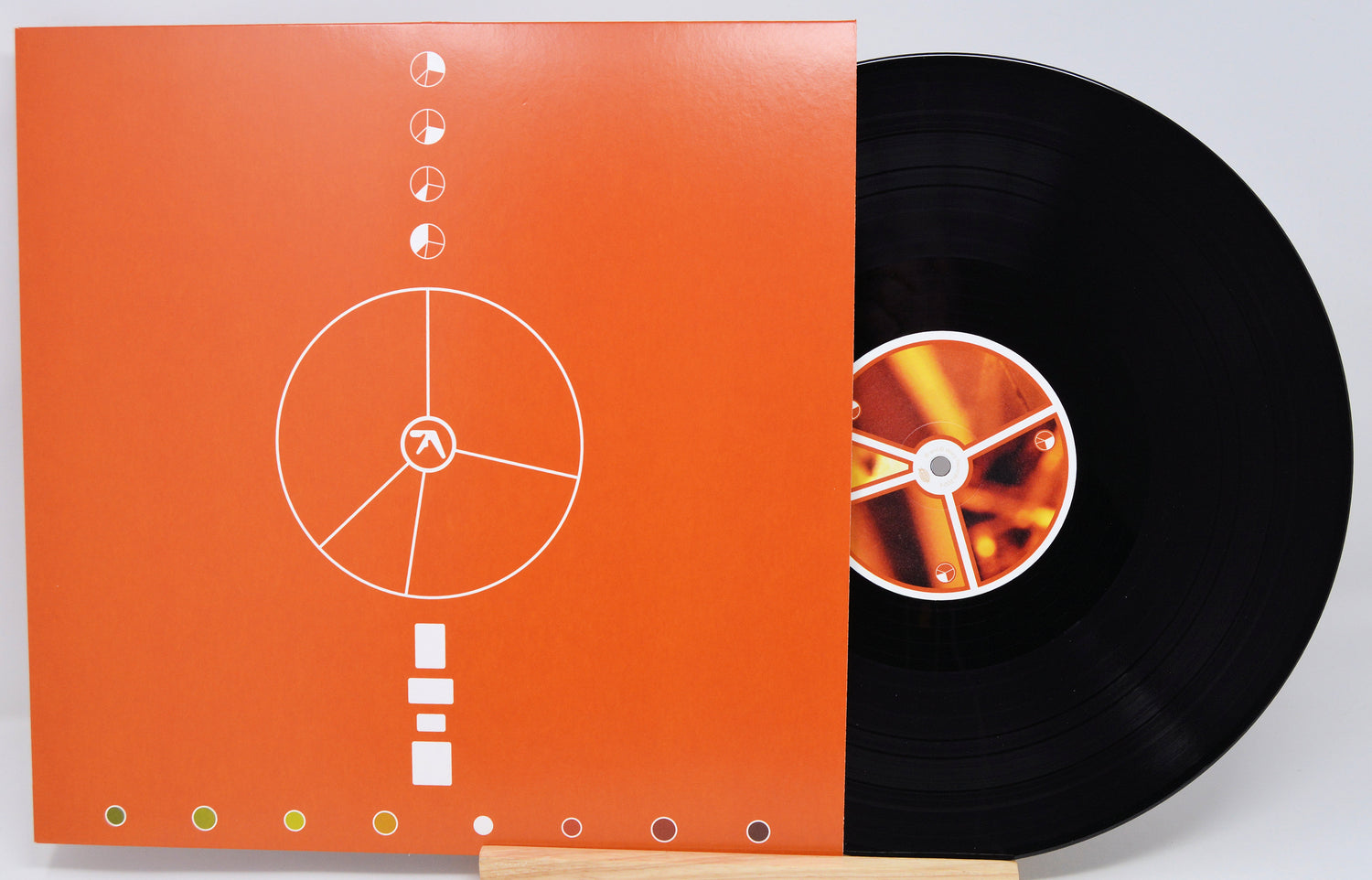 Vinyl record with orange cover featuring a white design on a light gray background