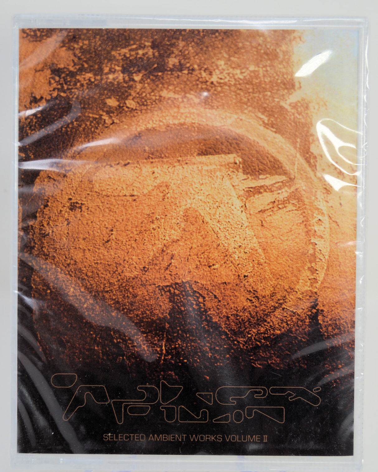 Aphex Twin Selected Ambient Vol II Cassettes Front cover with abstract design and text on a reflective surface