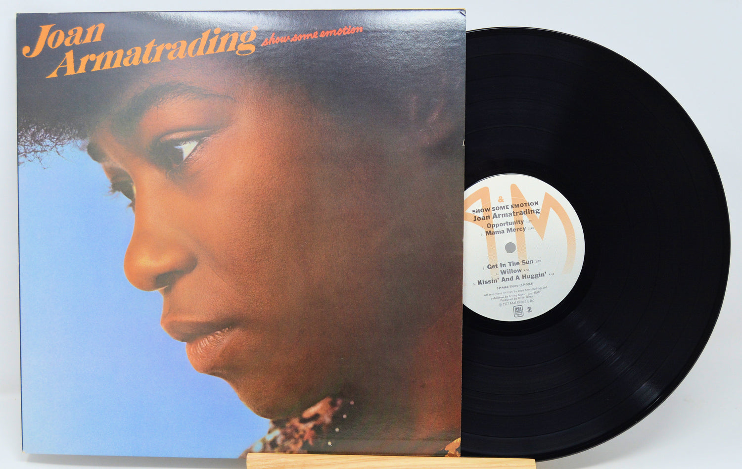 Vinyl record with cover featuring a close-up of a person's face, on a light gray background.