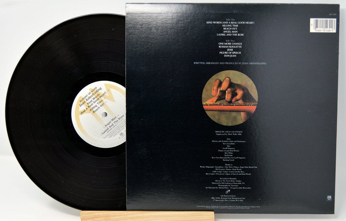 A vinyl record titled 'Sleight Of Hand' by Joan Armatrading with the album cover showing the artist's face and a guitar. The record is placed in front of the cover.