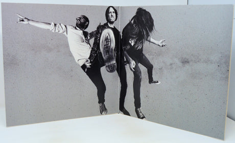 Black and white photo of three people in a dynamic pose on a textured gray background