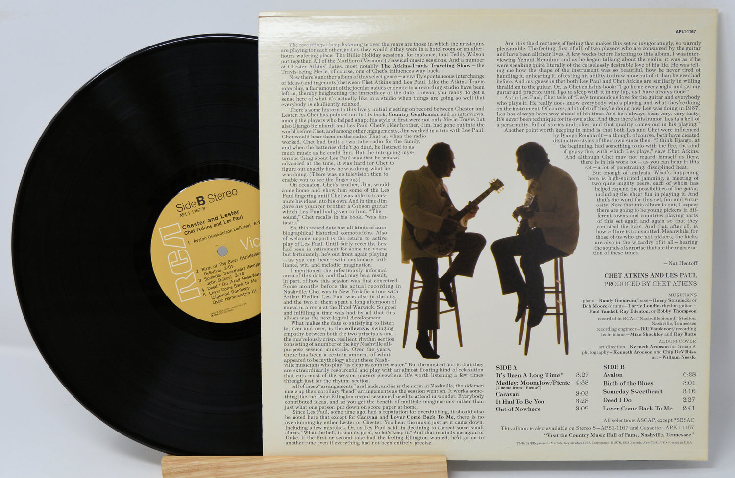 A vinyl record titled 'Chester & Lester' by Chet Atkins & Les Paul with a photo of the artists on the cover, smiling and holding guitars. The record is placed on a wooden stand.