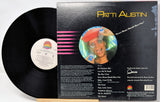 A vinyl record partially pulled from its black outer sleeve, showing the back cover artwork and track list. The record label includes Patti Austin and a colorful circular portrait on the cover.