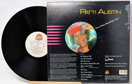 A vinyl record partially pulled from its black outer sleeve, showing the back cover artwork and track list. The record label includes Patti Austin and a colorful circular portrait on the cover.