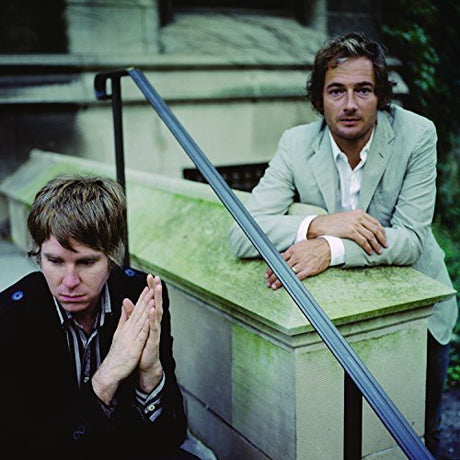 Two men sitting on a stone bench with a reflective surface behind them