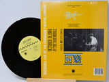 Vinyl record with yellow cover featuring text and images on a light gray background