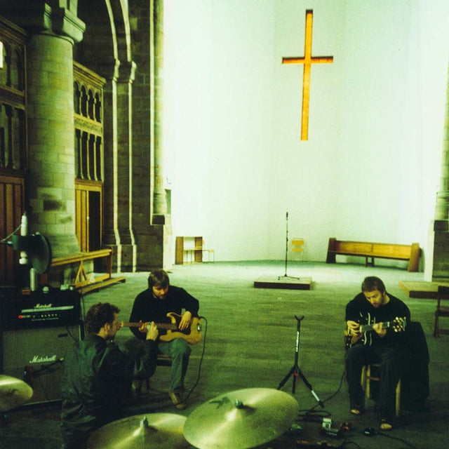 Three musicians performing with instruments inside a spacious church, illuminated by a cross-shaped window.