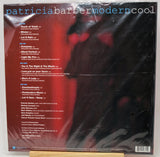 The back cover of a vinyl record sleeve for Patricia Barber / Modern Cool, wrapped in clear plastic. The cover features a dark red and black abstract background with white and blue text listing the tracks and artist name.