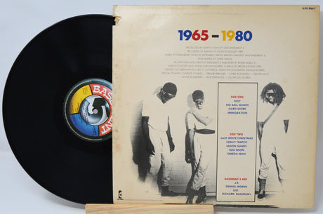 Vinyl record with a cover featuring a group of people and text spanning from 1965 to 1980.