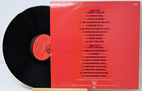 Vinyl record with red cover displaying tracklist on a light gray background