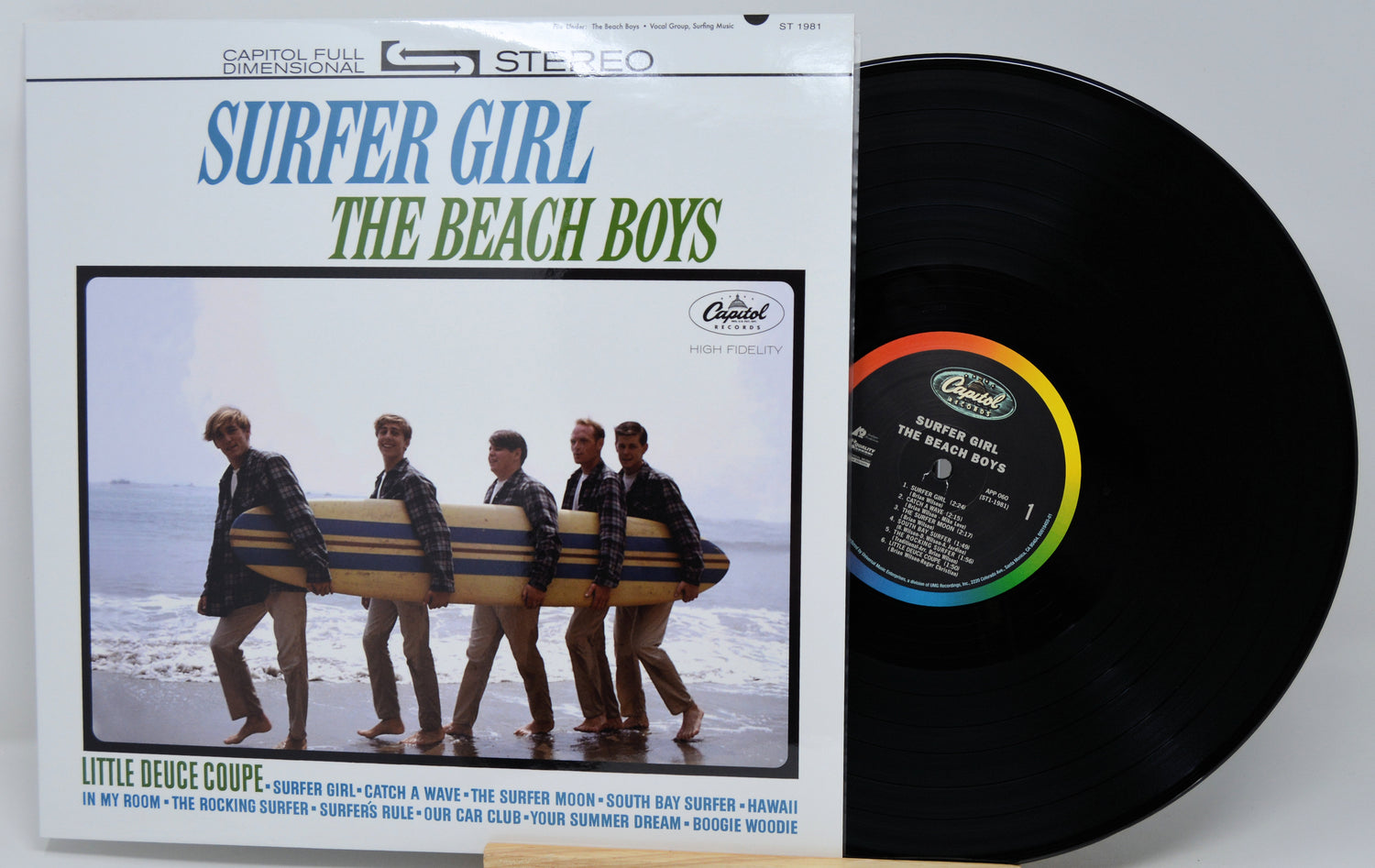 The Beach Boys 'Surfer Girl' vinyl record album with the outer paper sleeve visible on the left and the black LP record partially pulled out on the right, photographed against a plain light background.