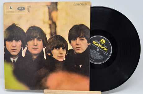 The image shows a vinyl record of The Beatles album 'For Sale' with the band members' faces on the cover.
