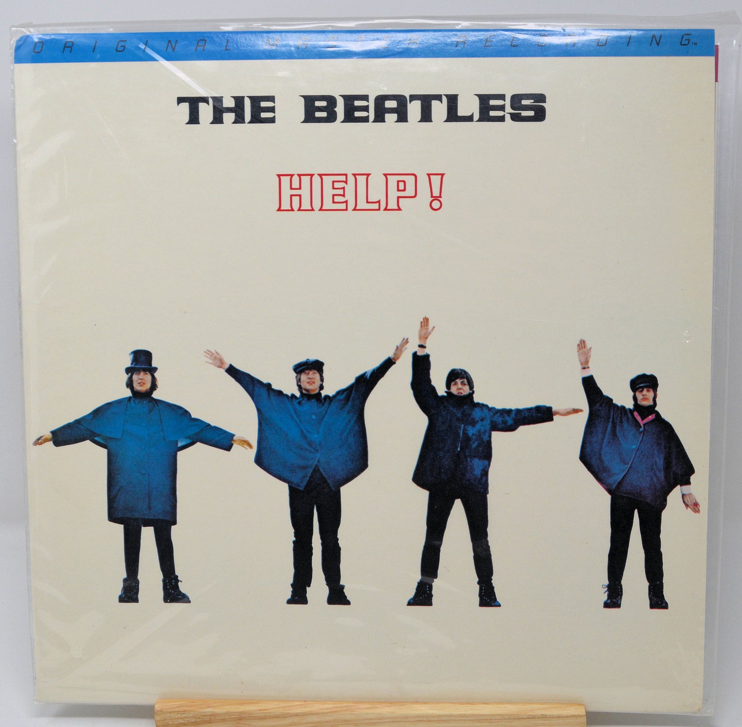 Vinyl record cover for 'The Beatles Help!' with four band members in blue raincoats on a beige background.