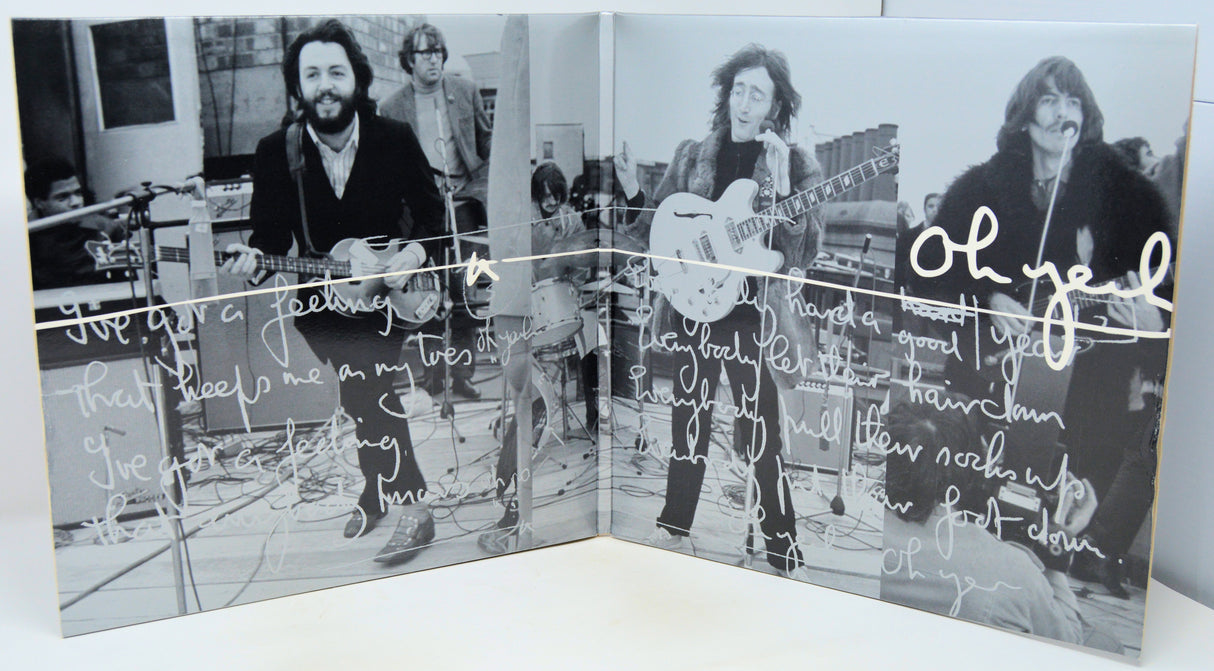 A square black-and-white printed artwork or album-cover style panel showing three musicians performing, overlaid with handwritten white text and signatures, photographed against a light neutral background.