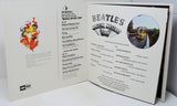 Open book or menu with 'The Beatles' Magical Mystery Tour' design on a white background