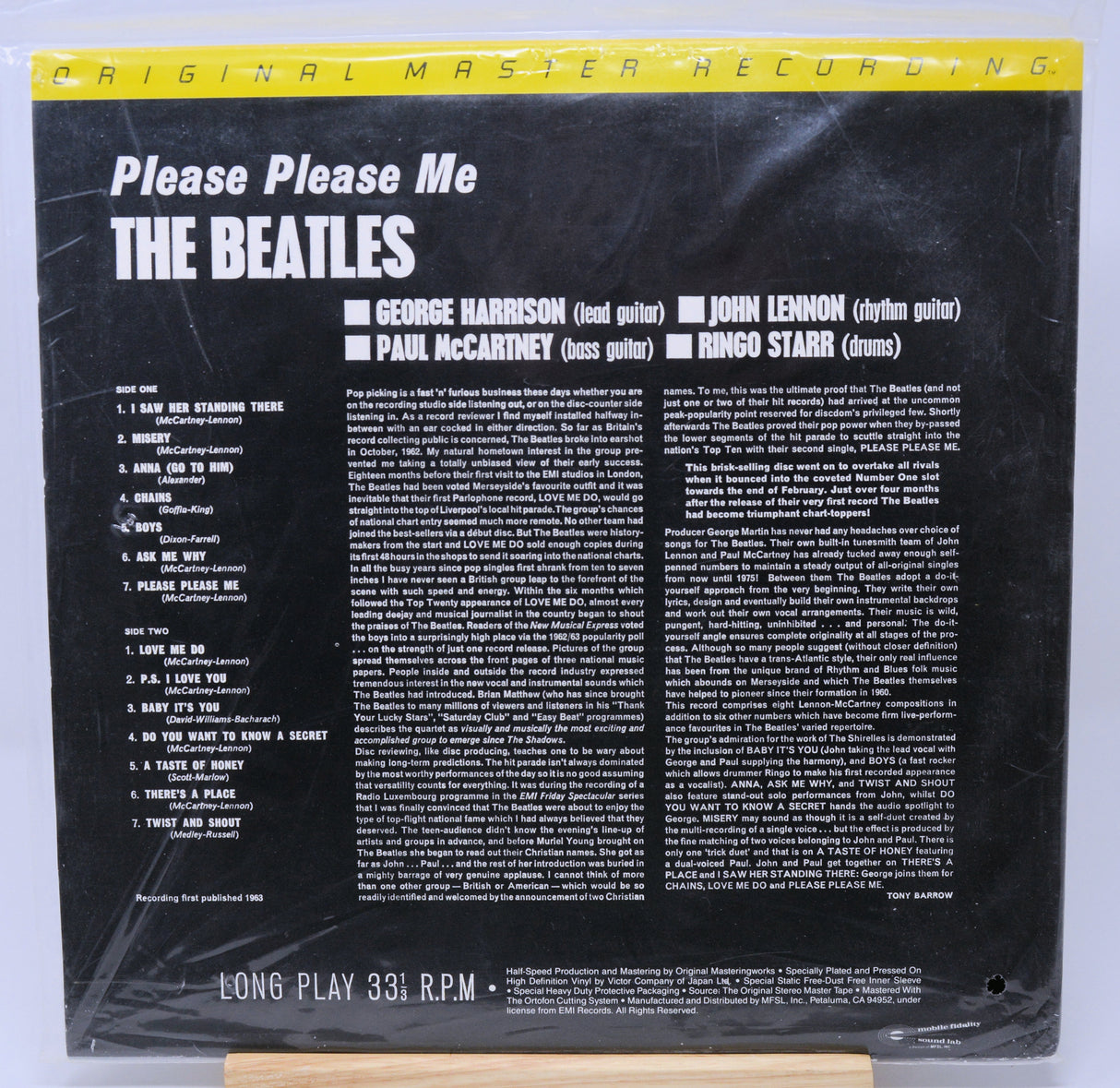 Vinyl record cover for 'Please Please Me' by The Beatles with yellow text and a photo of the band members.