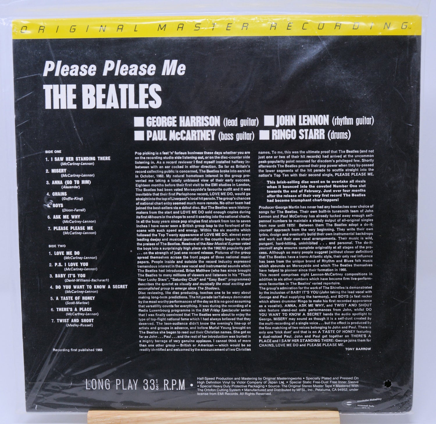 Vinyl record cover for 'Please Please Me' by The Beatles with yellow text and a photo of the band members.