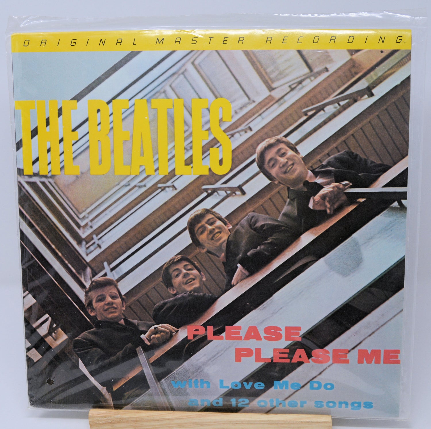 Vinyl record cover for 'Please Please Me' by The Beatles with yellow text and a photo of the band members.