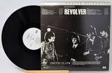 Vinyl record and cover of 'Revolver' by The Beatles on a white background
