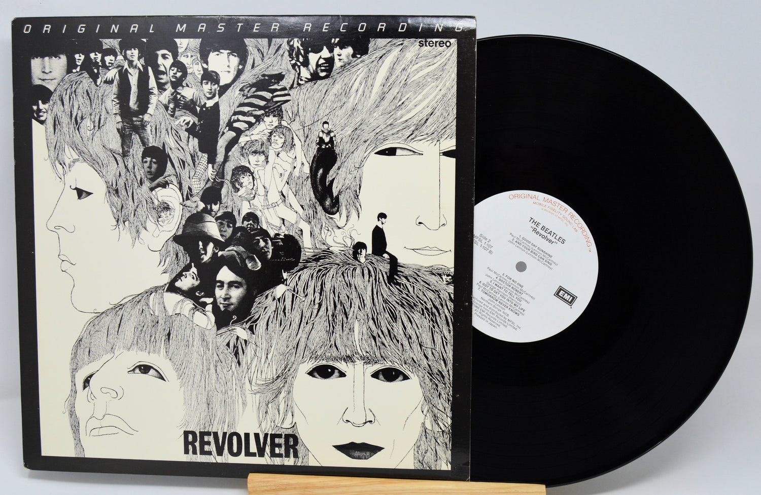 Vinyl record with cover featuring artistic design of faces and text 'Revolver'.