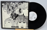 Vinyl record with cover featuring artistic design of faces and text 'Revolver'.