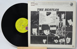 Vinyl record with cover featuring The Beatles' album art on a light gray background