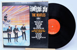 Vinyl record and cover of 'Something New' by The Beatles on a light blue background