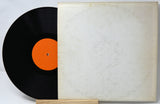 Vinyl record with orange label and white cover on a light gray background