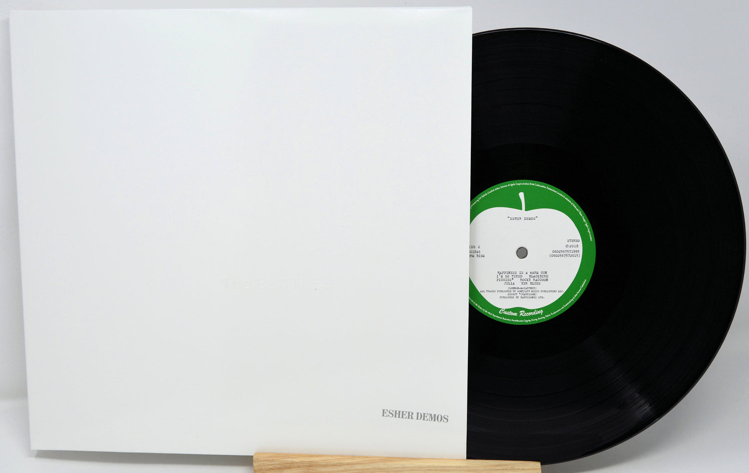 Vinyl record with a green label and white sleeve on a light gray background