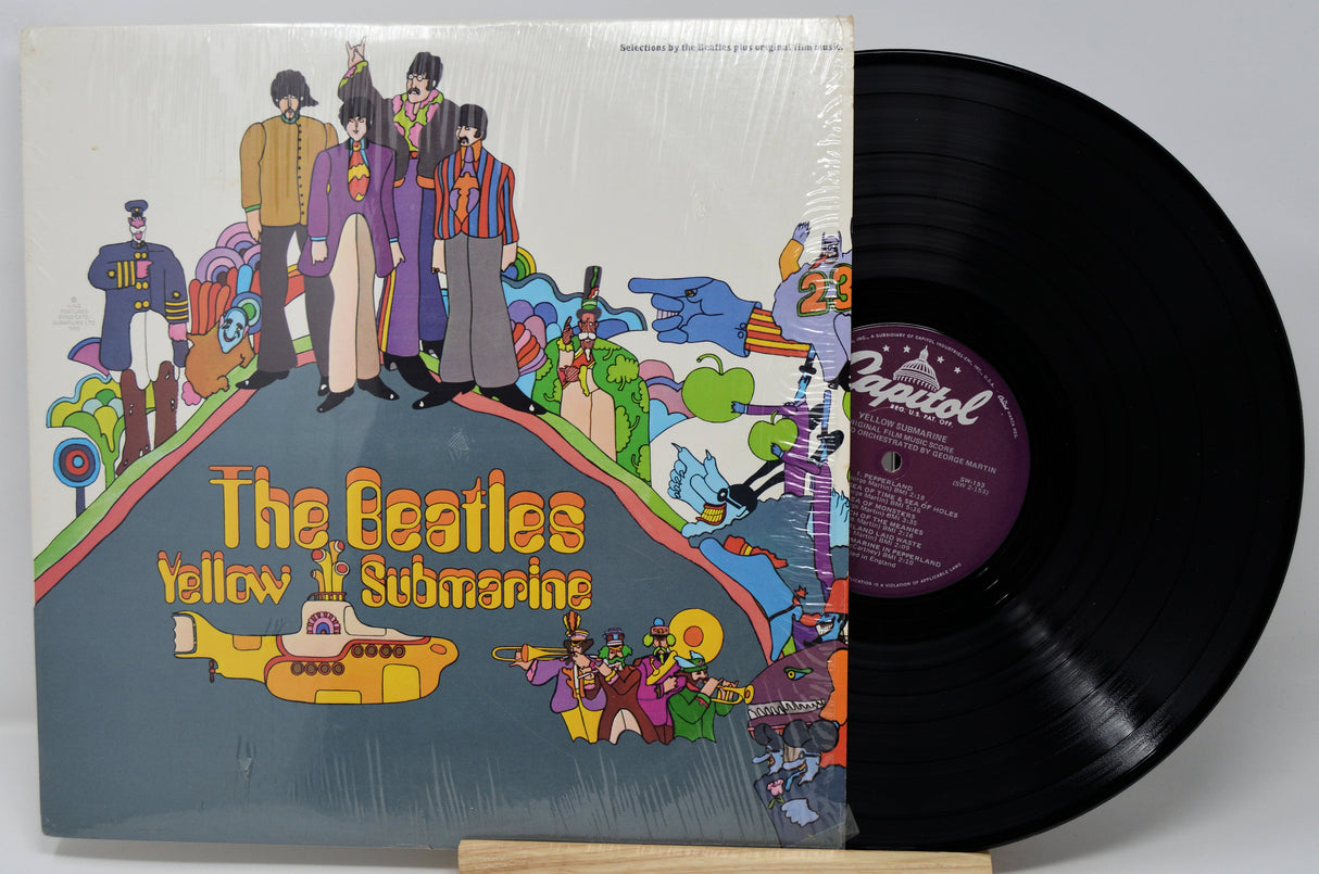 Vinyl record with 'The Beatles Yellow Submarine' cover showing band members and colorful design.