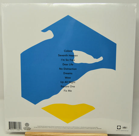 The back cover of a vinyl record sleeve for Bob Dylan's album 'Colors', showing a white background with a blue abstract shape, a yellow shape, and a list of track titles.
