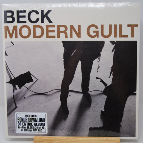 Beck's 'Modern Guit' vinyl record cover, sealed in plastic and displayed on a wooden stand. The cover features a black and white photograph of musicians with the title in bold brown and black lettering.