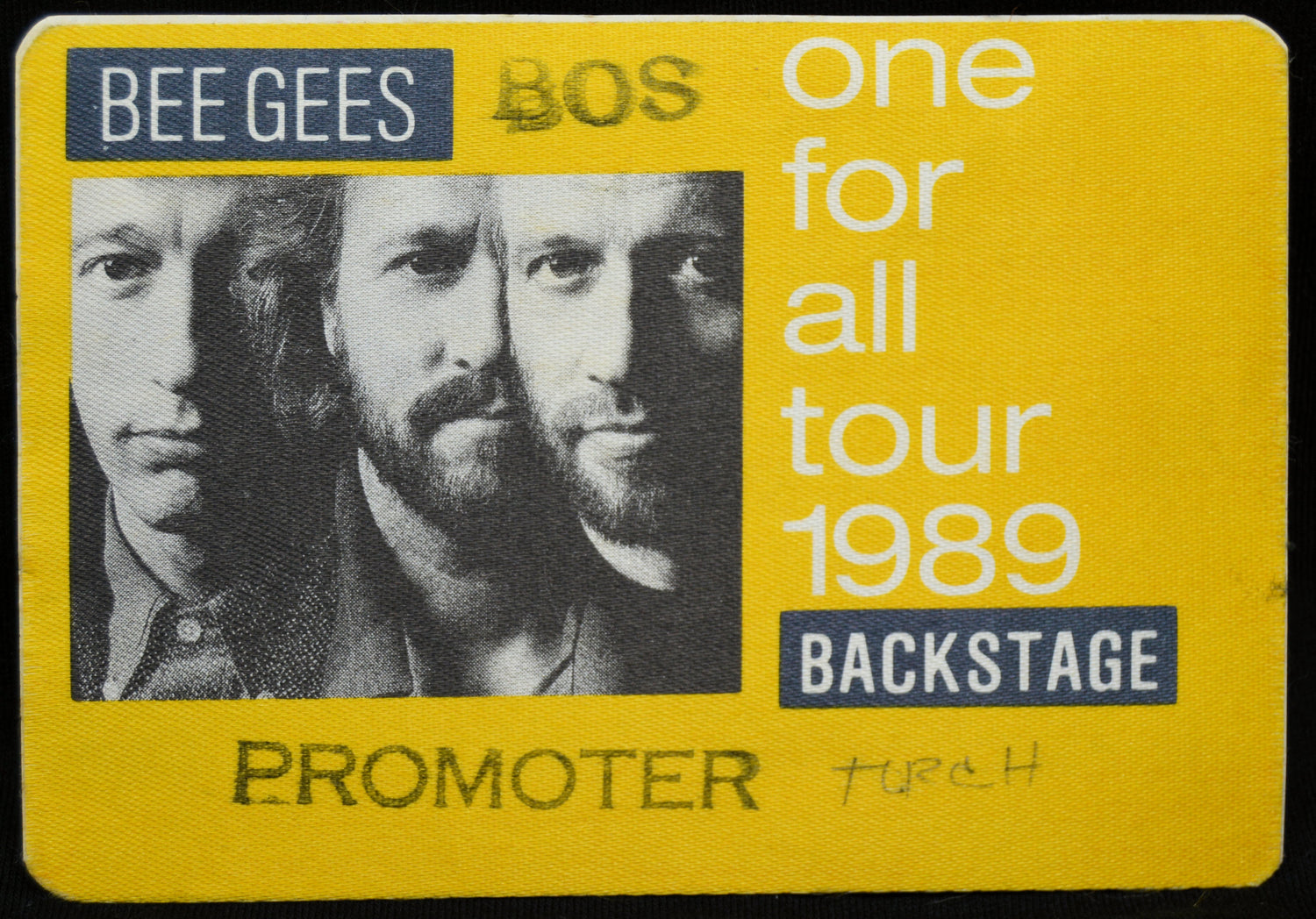 Backstage pass for Bee Gees concert tour in 1989 with yellow border and black and white photo of three men.